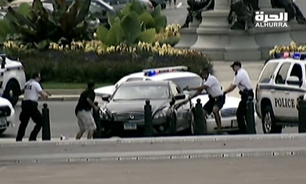 This image from video provided by Alhurra Television shows police with guns drawn surrounding a black Infiniti near the U.S. Capitol in Washington, Thursday, Oct. 3, 2013. A woman with a young child inside tried to ram through a White House barricade, then led police on a chase toward the Capitol, where police shot and killed her, witnesses and officials said. (AP Photo/Alhurra Television)