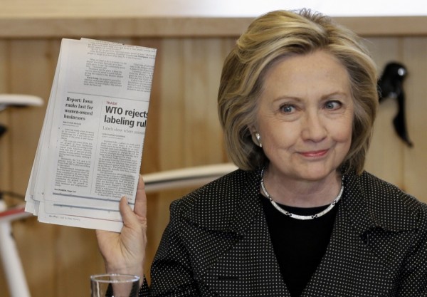 Democratic presidential candidate Hillary Rodham Clinton holds up a newspaper as she speaks to small business owners, Tuesday, May 19, 2015, at the Bike Tech cycling shop in Cedar Falls, Iowa. (AP Photo/Charlie Neibergall)